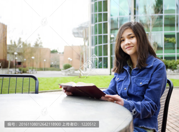 十二歲的混血女孩坐在戶外閱讀一本書(shū)