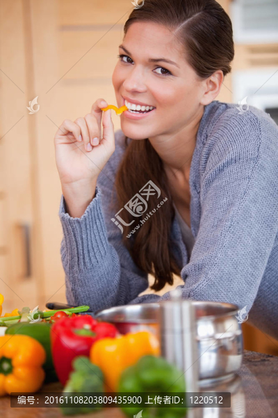 微笑的女人在廚房里吃甜椒