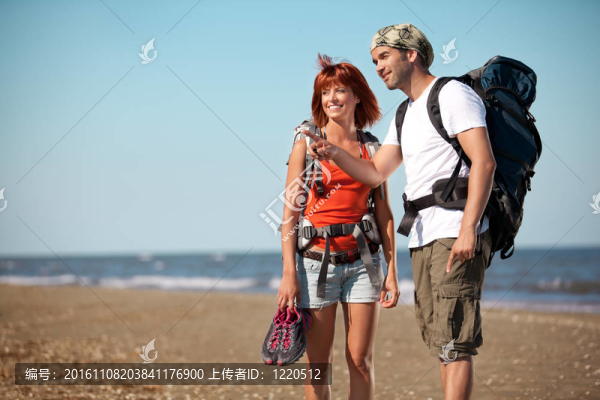 背著書包走在海邊的情侶