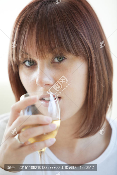 迷人的年輕女子喝了一杯白葡萄酒