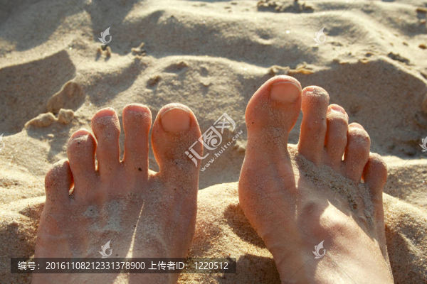 人腿躺在海岸上的熱砂