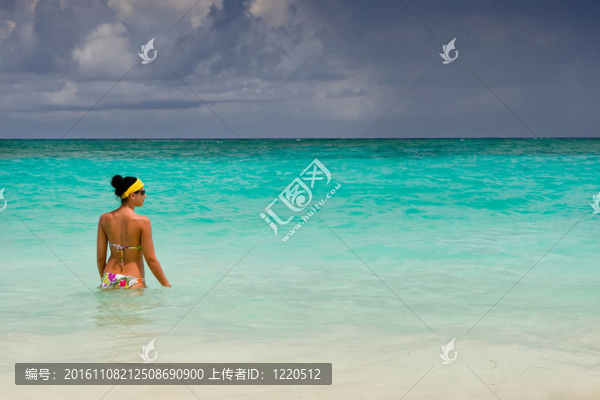 曬黑的女孩站在明亮的藍(lán)色海洋