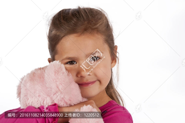 年輕女孩與粉紅色的衣服擁抱泰迪在工作室
