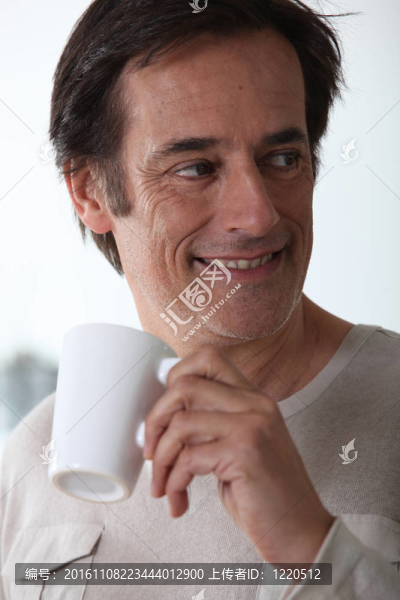 男子笑著喝著一杯茶。