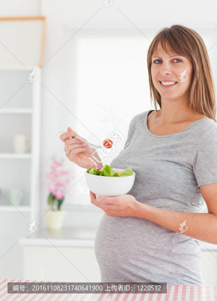迷人的孕婦吃櫻桃番茄站