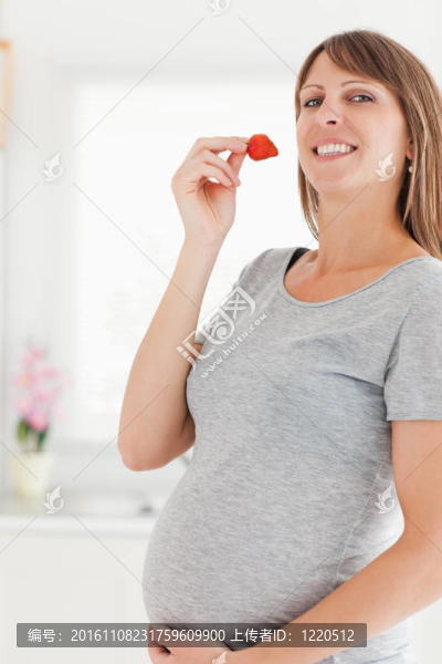 美麗的孕婦站著吃草莓