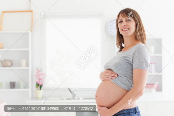 美麗的孕婦的姿勢在撫摸她的肚子