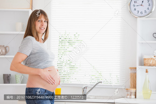 美麗的孕婦撫摸著她的肚皮站立