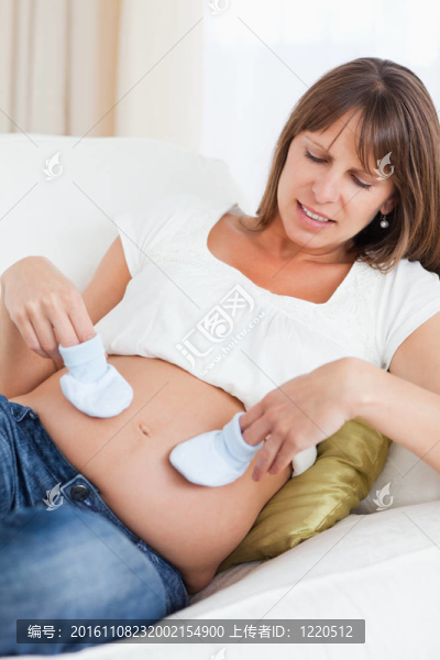 迷人的孕婦玩嬰兒鞋，而說謊