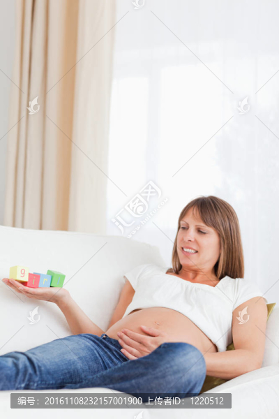 迷人的孕婦玩積木和有字女孩寫(xiě)在她的手，而躺在沙發(fā)上