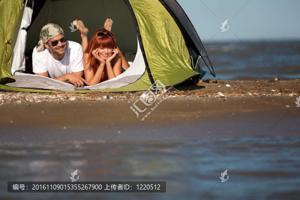 快樂的年輕夫婦坐在帳篷海邊