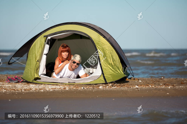 快樂的年輕夫婦坐在帳篷海邊