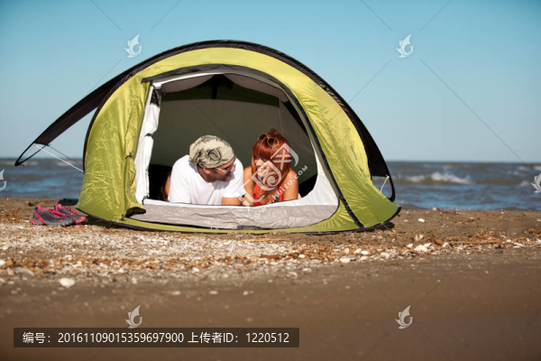快樂的年輕夫婦坐在帳篷海邊