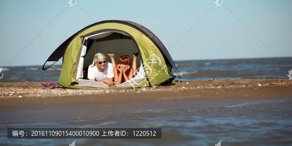 快樂(lè)的年輕夫婦坐在帳篷海邊