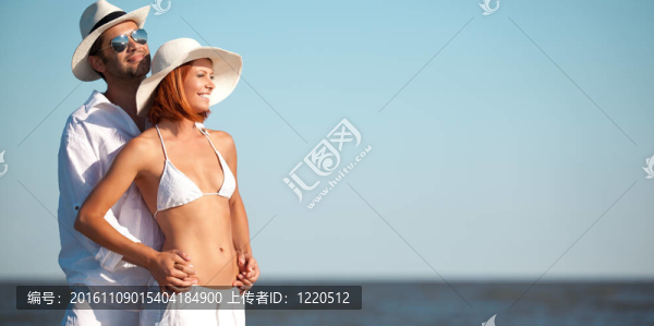 快樂的年輕情侶站在海灘上