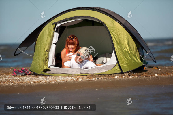快樂的年輕夫婦坐在帳篷海邊