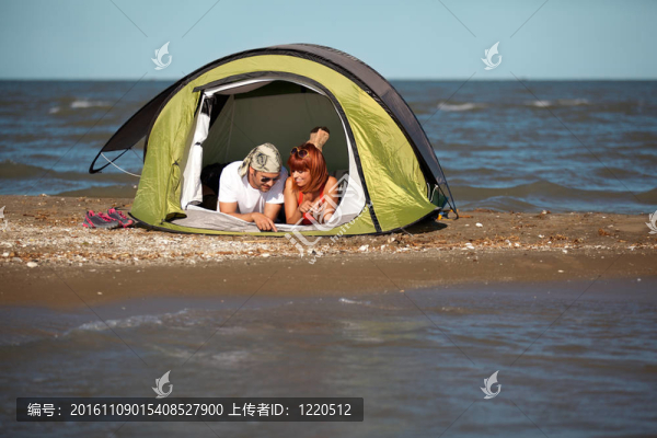 快樂的年輕夫婦坐在帳篷海邊