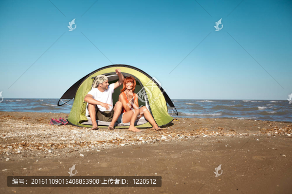 快樂(lè)的年輕夫婦坐在帳篷海邊