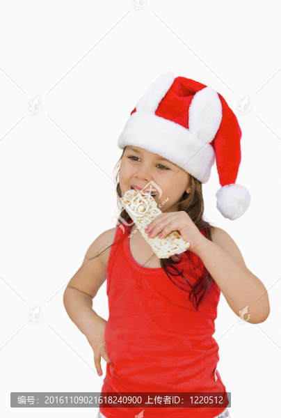 小女孩戴紅色Santa帽吃白巧克力花生