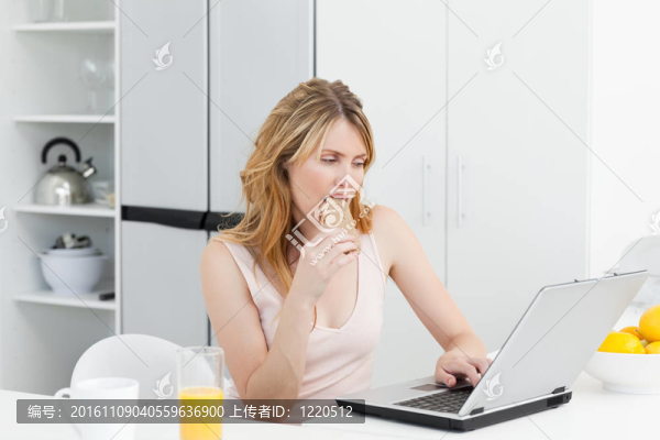 女人一邊喝一邊看著她的筆記本電腦