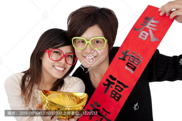 新年快樂。年輕夫婦拿著元寶和紅春聯(lián)
