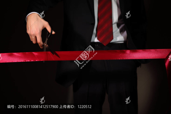 用剪刀切一個紅絲帶的商人