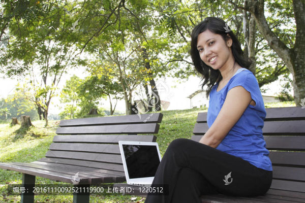 女人在長凳上使用筆記本電腦