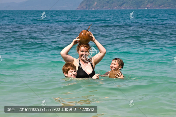 家庭在海邊玩椰子在美麗的海灘上