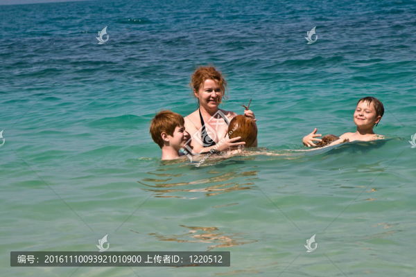 家庭在海邊玩椰子在美麗的海灘上