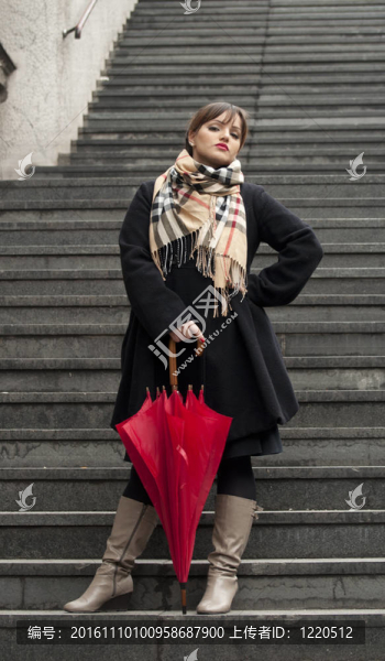 美女帶著嚴(yán)肅的目光拿著紅色的傘在樓梯上