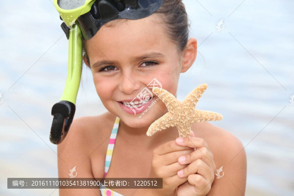 小女孩在海灘上抱著明星魚