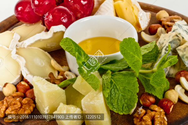 各種帶蜂蜜的奶酪；盤子上的堅果和葡萄；在白色上分離