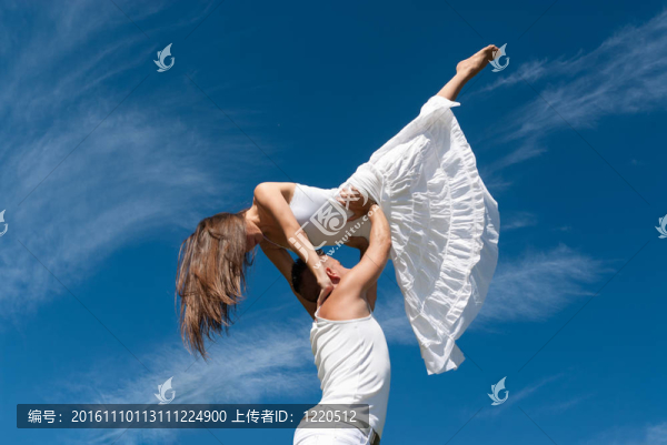 在天空背景下跳舞的年輕夫婦；自由和放松的象征