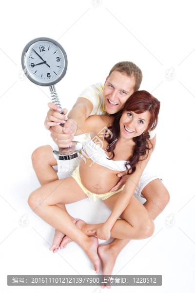 與丈夫快樂的孕婦肖像；舉行時鐘顯示第九個月；焦急等待嬰兒的誕生。第三孕期。在白。