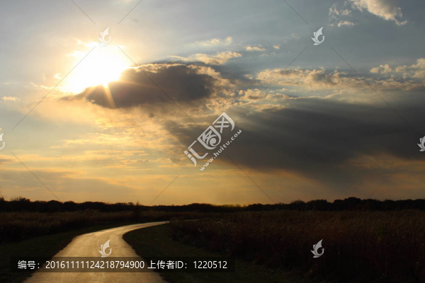 太陽穿過云層在一條孤獨的路上