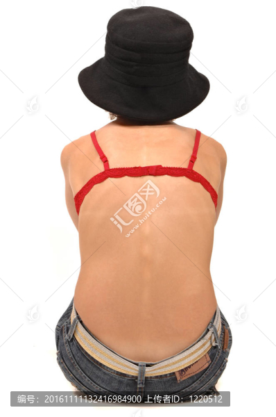 美麗的年輕女子穿著帽子和牛仔褲坐在地板上