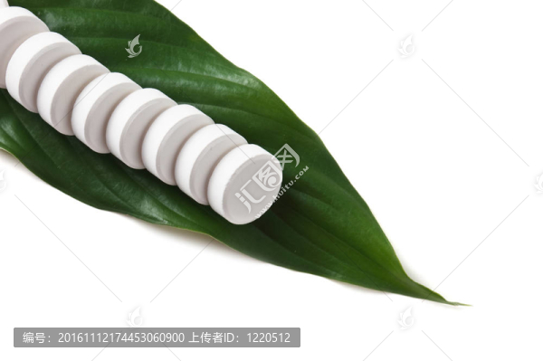 躺在一片綠葉上的白色藥丸
