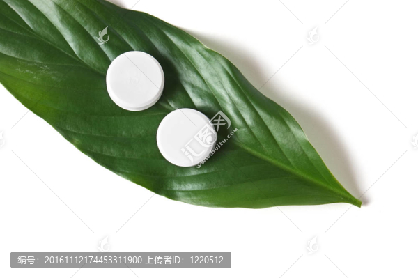 躺在一片綠葉上的白色藥丸