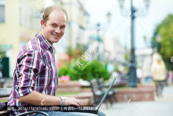 面帶微笑的男子帶著筆記本電腦