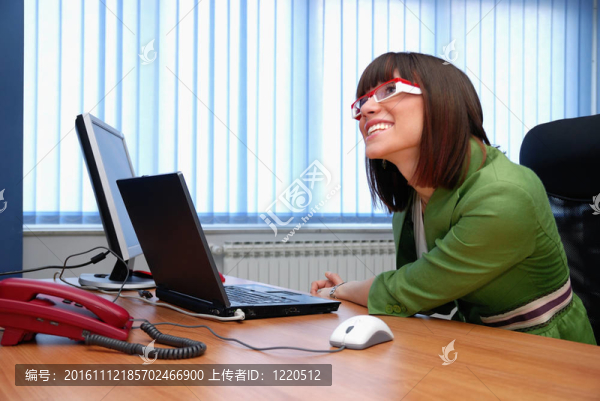 微笑的年輕女商人正在辦公室里一臺筆記本電腦。