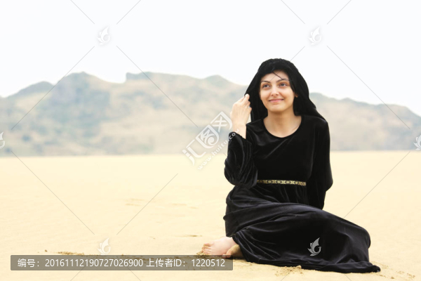 裹著披肩的女人坐在沙灘上
