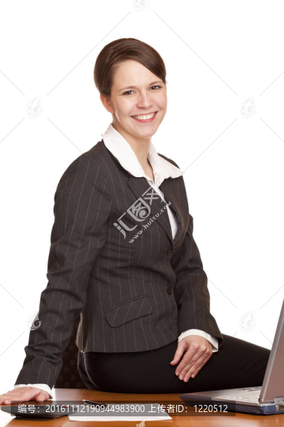 坐在辦公桌上的迷人快樂的商業(yè)女性