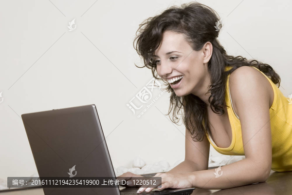 笑的女孩躺在地板上的筆記本電腦