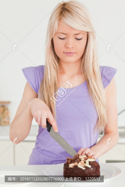 漂亮的金發(fā)女人在盤子里切蛋糕