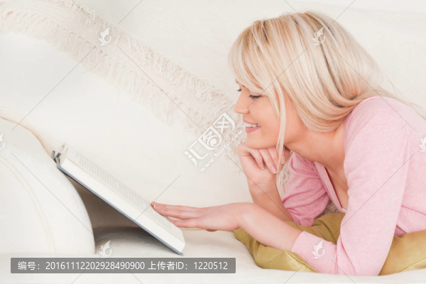 年輕漂亮的女人躺在沙發(fā)上看書