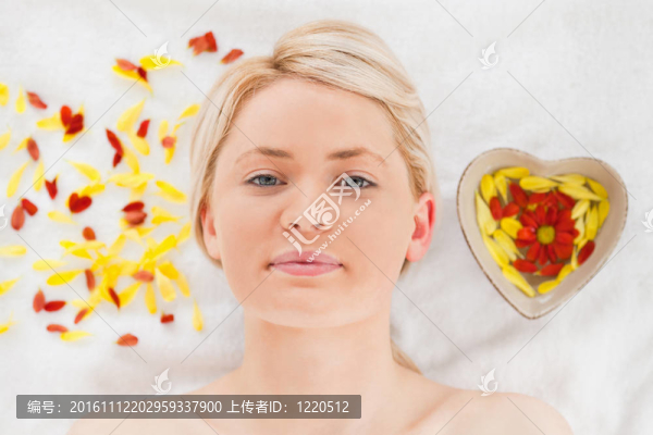 迷人的金發(fā)女子躺在溫泉中心附近的花瓣旁