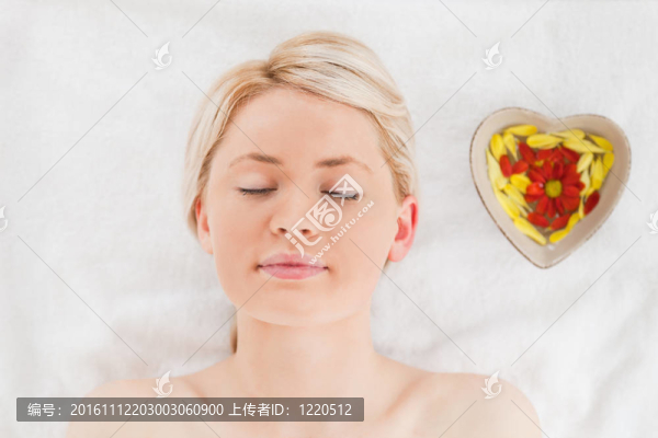 年輕的金發(fā)女郎躺在花瓣附近