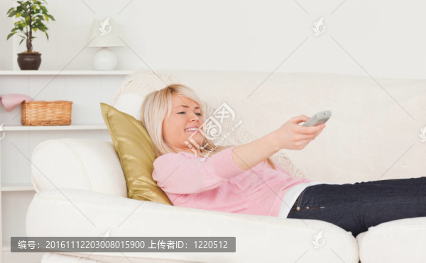 好看的金發(fā)女躺在沙發(fā)上看電視