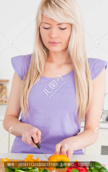 微笑的金發(fā)女子在現(xiàn)代廚房室內(nèi)切割辣椒