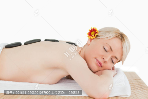 可愛的金發(fā)女人放松與熱石頭在她的背上